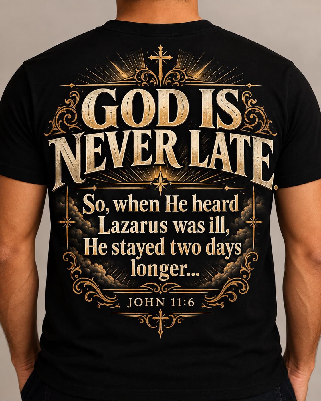 Back of a black tee printed God is never late with John 11:6 and gold scrollwork.